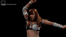 two women are wrestling in a wrestling ring and one of them is laying on the ground .