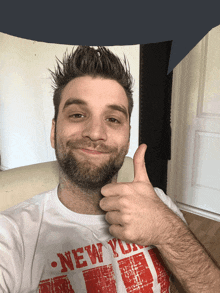 a man giving a thumbs up wearing a new york t-shirt