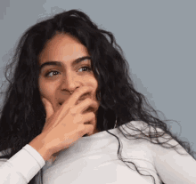 a woman with long hair is covering her mouth with her hand