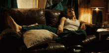 a man is laying on a couch with his feet up