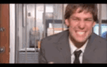 a man in a suit and tie is smiling and making a funny face behind bars .