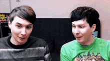 two men are sitting next to each other on a couch and looking at each other .