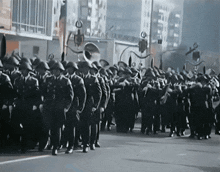 a group of soldiers march down a street in front of a building that says ' allianz ' on it