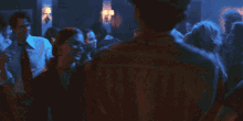 a man in a white shirt and tie is dancing in a crowded room