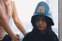 a woman wearing a blue hard hat with a yellow mcdonald 's logo on it