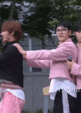 a man in a pink jacket is holding another man 's shoulder .
