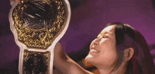 a woman is holding up a gold and silver wrestling championship belt