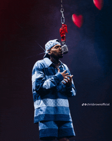 chris brown is singing into a microphone with a heart hanging from it