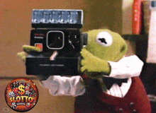 kermit the frog is holding a polaroid camera in front of a sign that says lotto