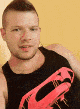 a man in a black tank top with a red superman logo on it