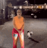 a woman is standing in a parking lot with a small dog .