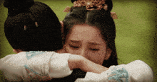 a woman with a crown on her head hugging another woman