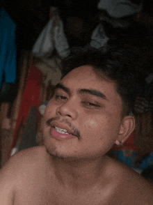 a shirtless man with a beard is smiling