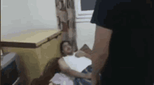 a man is standing next to a woman who is laying on a bed .