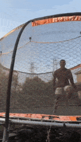 a man is jumping on a trampoline with a chicken wire net behind him .