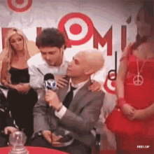 a man in a suit is talking into a microphone in front of a target sign