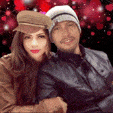 a man and a woman are posing for a picture with hearts behind them