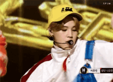 a person wearing a yellow hat and overalls is singing into a microphone on a stage .