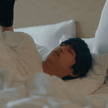 a man with blue hair is laying on a bed with his eyes closed