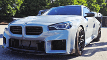 a silver bmw is parked in front of a fence