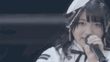 a girl is singing into a microphone with the letters tbs in the background