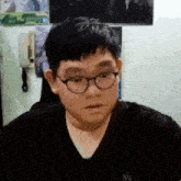 a man wearing glasses and a black shirt with the letter n on the front