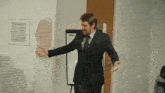 a man in a suit and tie is dancing in front of a white board