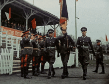 a group of soldiers march in front of a sign that says deutschen demokrat
