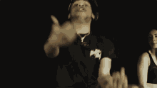 a man is making a funny face in a dark room while wearing a necklace .