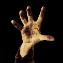 a dirty hand is reaching out towards the camera on a black background