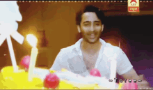 a man is standing in front of a birthday cake with candles on it and says toree on the bottom