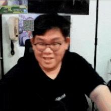 a man wearing glasses and a black shirt is smiling and looking at the camera .