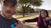 a man and a woman are standing next to each other in a parking lot and the woman has pink hair