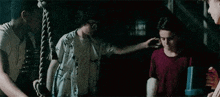 a group of young men are standing next to each other in a dark room holding a rope .