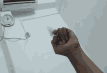 a person 's fist is being held up in front of a clock that shows the time as 10:13