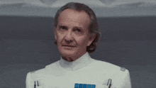 an older man in a white uniform with blue buttons on the sleeves