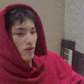 a man wearing a red hoodie is sitting in front of a piano keyboard