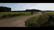 a person is riding a bike down a road in a field