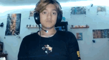 a young man wearing headphones and a black shirt with the letter b on the sleeve .
