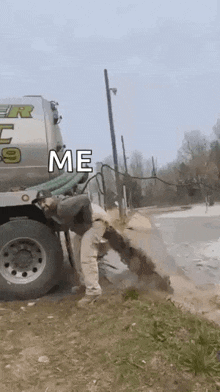 a man is digging a hole in the ground next to a large truck .