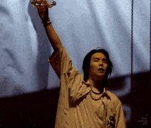 a man in a white shirt is holding a bottle of water in his hand on a stage .