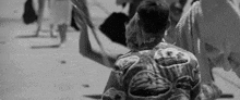 a man in a hawaiian shirt is walking on a beach .