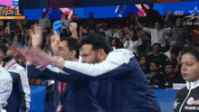 a man is hugging another man in front of a crowd at a cricket match