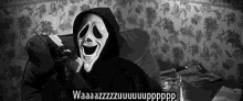 a person wearing a scream mask is sitting on a couch and talking on a cell phone .