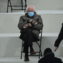 Bernie Sanders With Blue Medical Mask In Chair With Mittens GIF