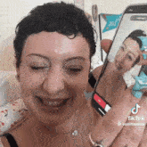 a woman is smiling while holding a cell phone that says tiktok