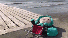 a stuffed animal is sitting in a small chair on the beach .