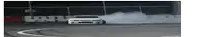 a white car is drifting on a track with smoke coming out of it