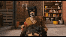 a cartoon character wearing a bear mask holds a red object