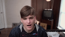 a young man is sitting in front of a tv with the words ' giggle.ai ' on the bottom of the screen